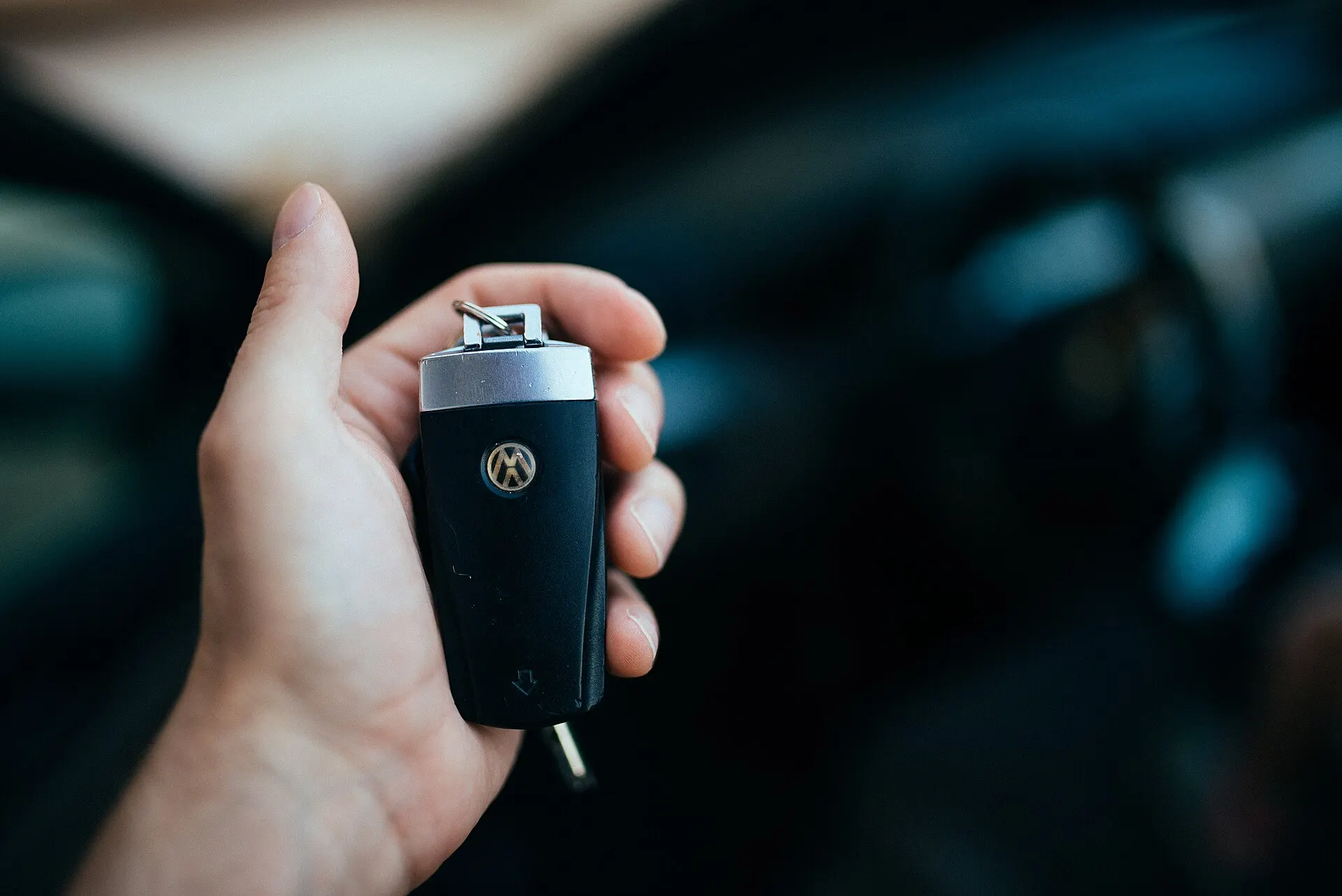 Ruka drži ključ automobila ispred auta, spremno za predaju novom vlasniku