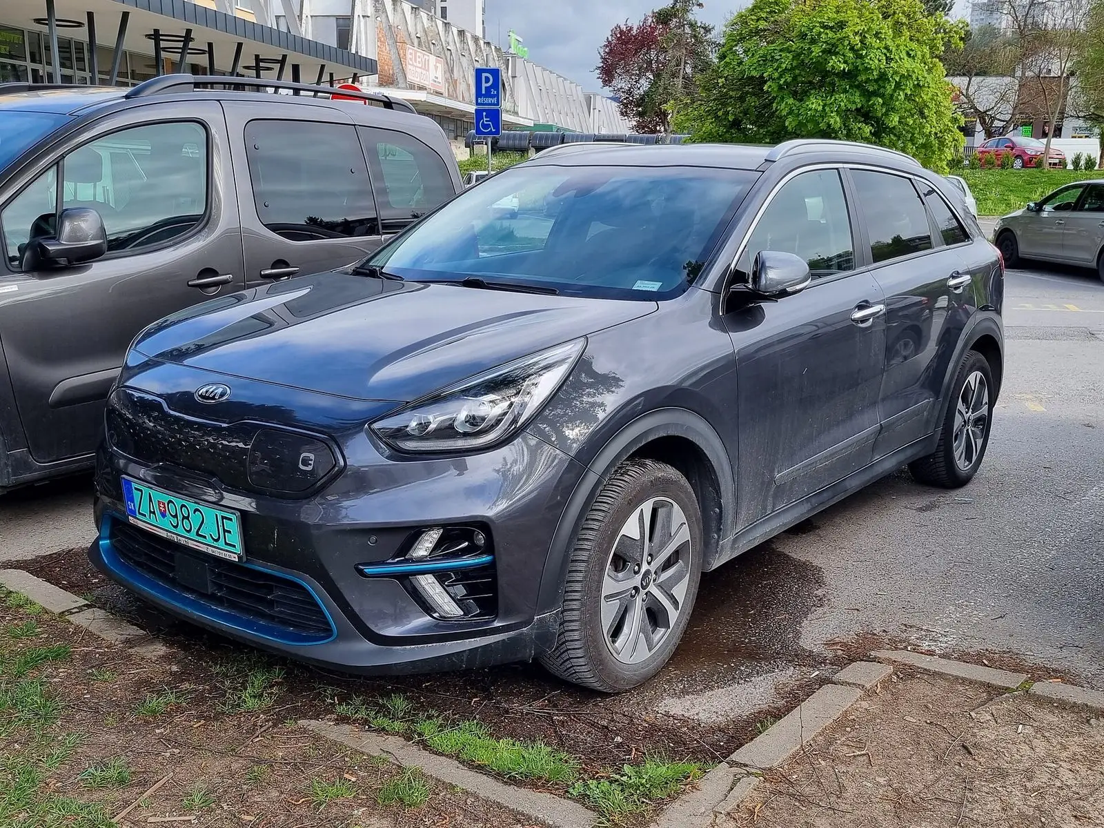 Kia e-Niro u tamnosivoj boji s plavim detaljima na braniku, pogled sprijeda sa strane