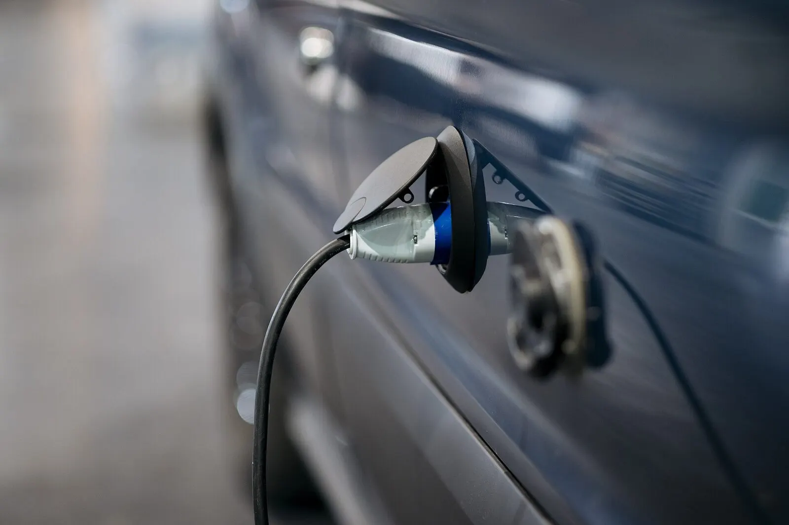 Kabel za punjenje utaknut u priključak plavog električnog automobila
